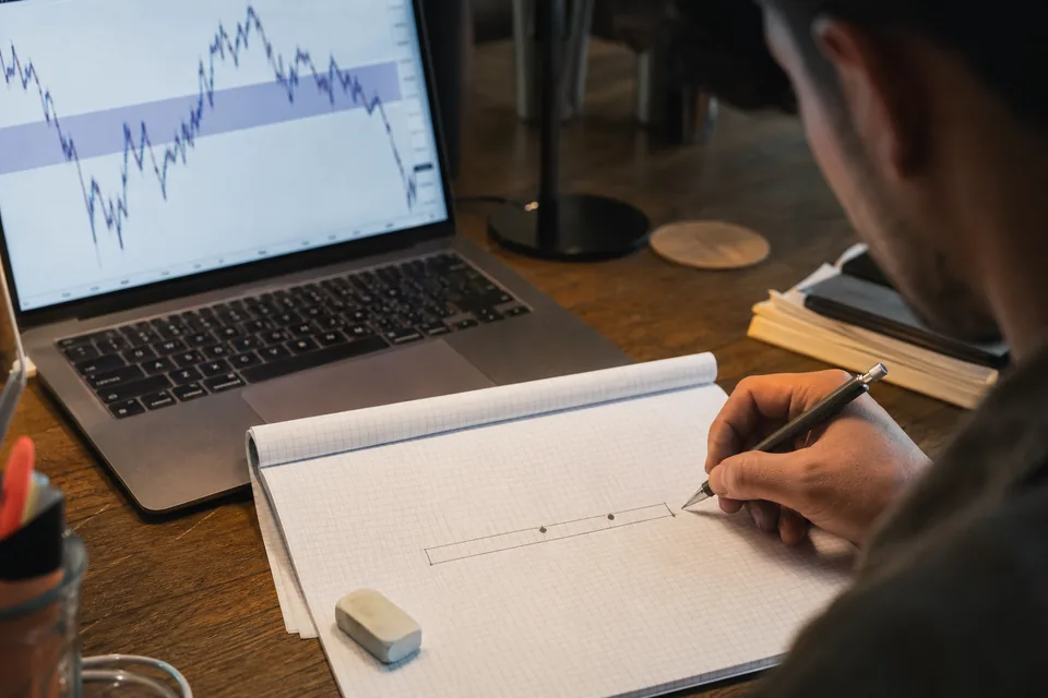 Notebook with a pencilled estimate range next to a chart