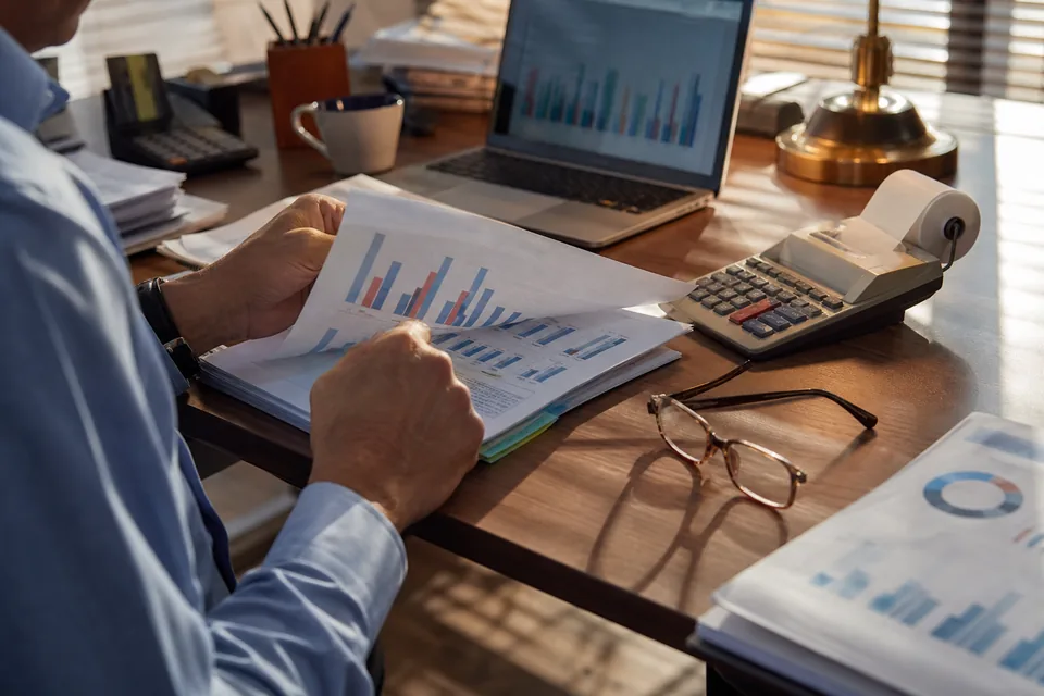 Revenue report with bar charts, a calculator and a laptop on a finance desk