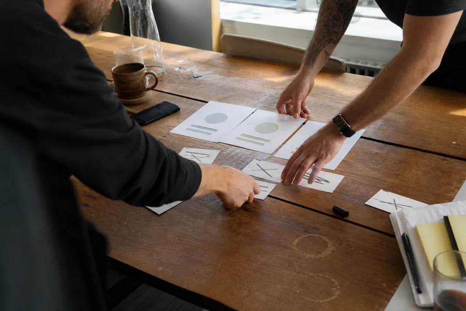 Hands rearranging printed plan cards during a pricing workshop