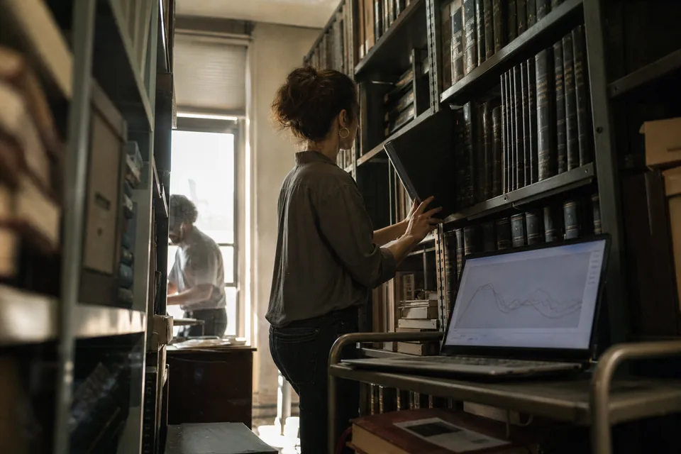 Editor in a magazine archive beside a laptop with crawler traffic